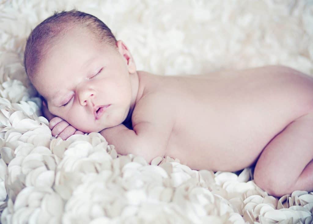 Cute naked newborn sleeping on fluffy blanket