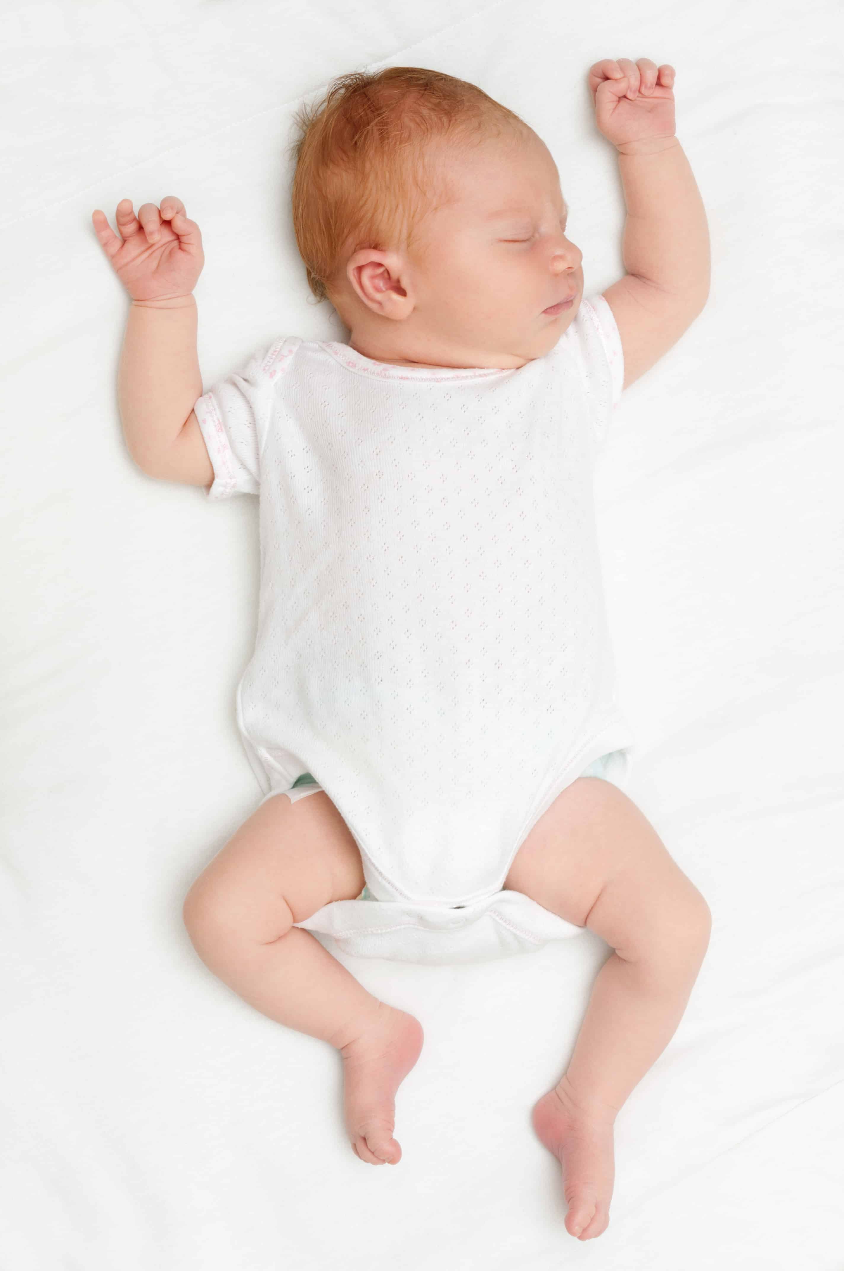 newborn baby sleeping on back without swaddle