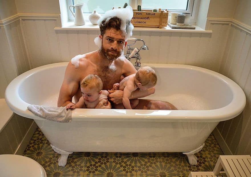 dad taking a bath with twins in clawfoot tub