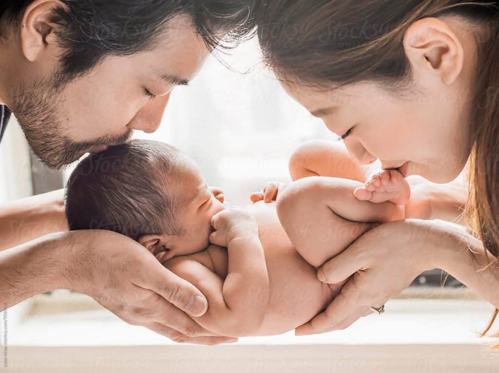 new parents holding naked newborn