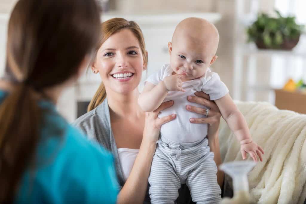 mom holding baby talking with sleep consultant
