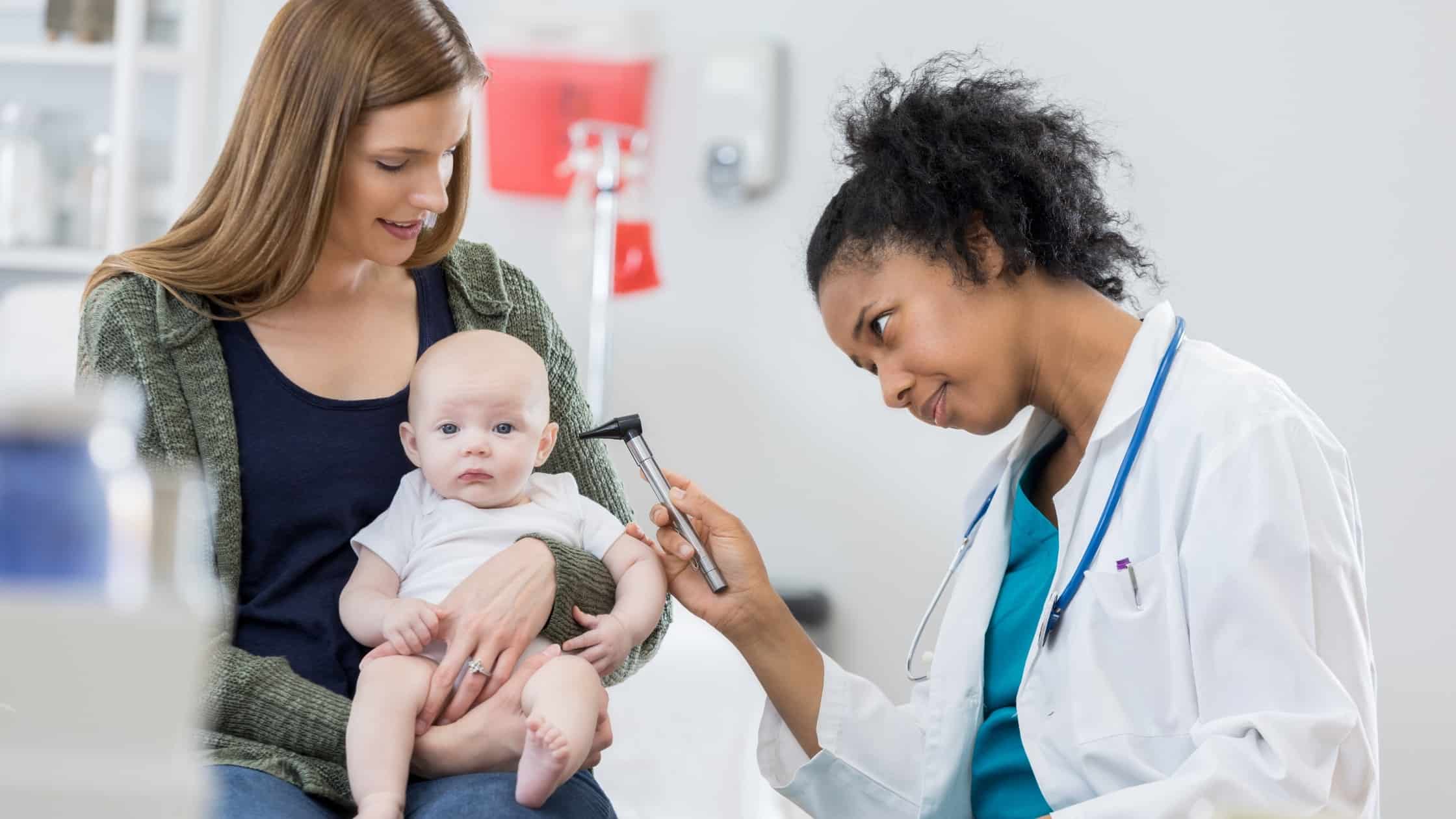 Mom holding baby while Doctor inspects ear