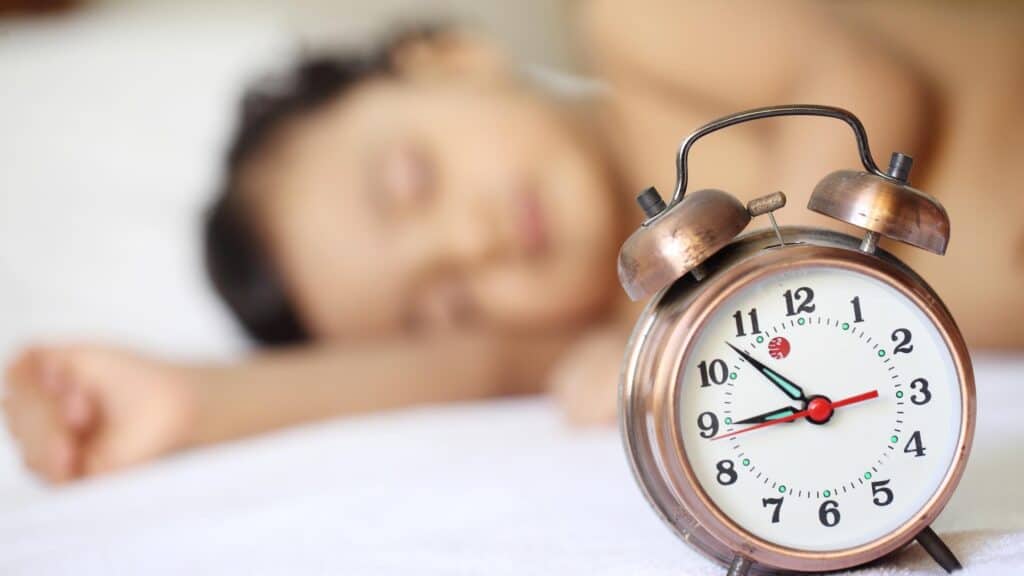 baby sleeping next to clock