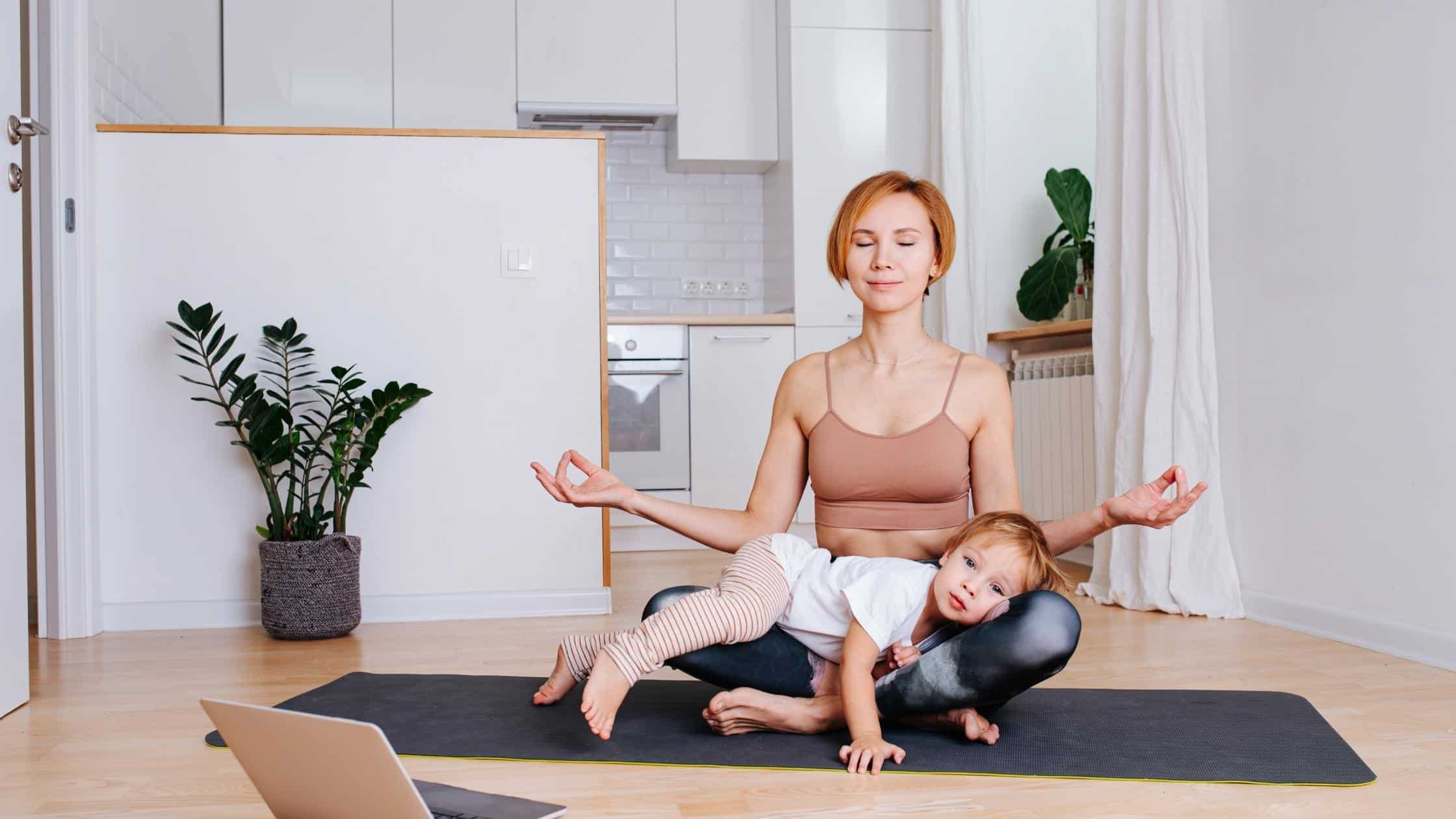 woman sitting in yoga position with toddler on lap