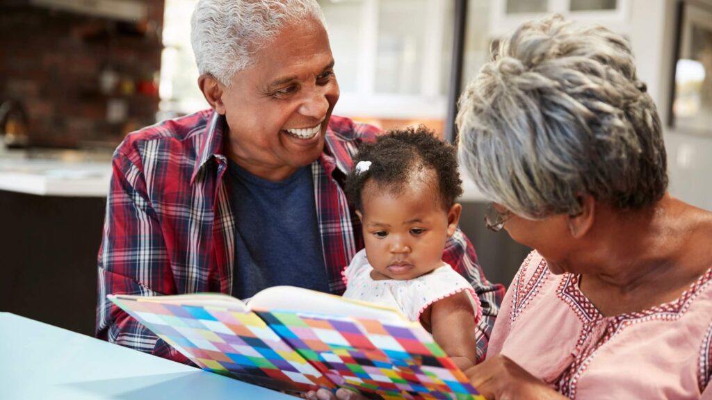 grandparents holding baby and reading to it