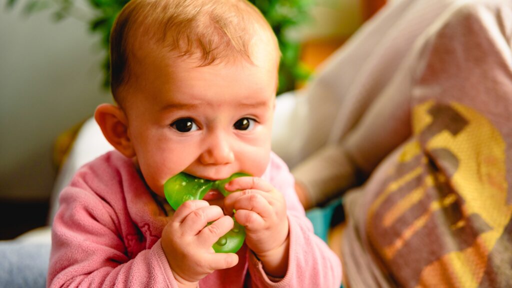 teething baby using a teether