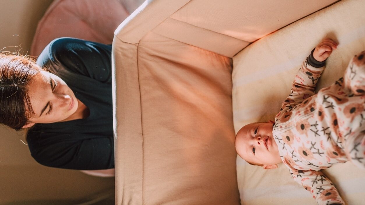 mom watching over baby in crib