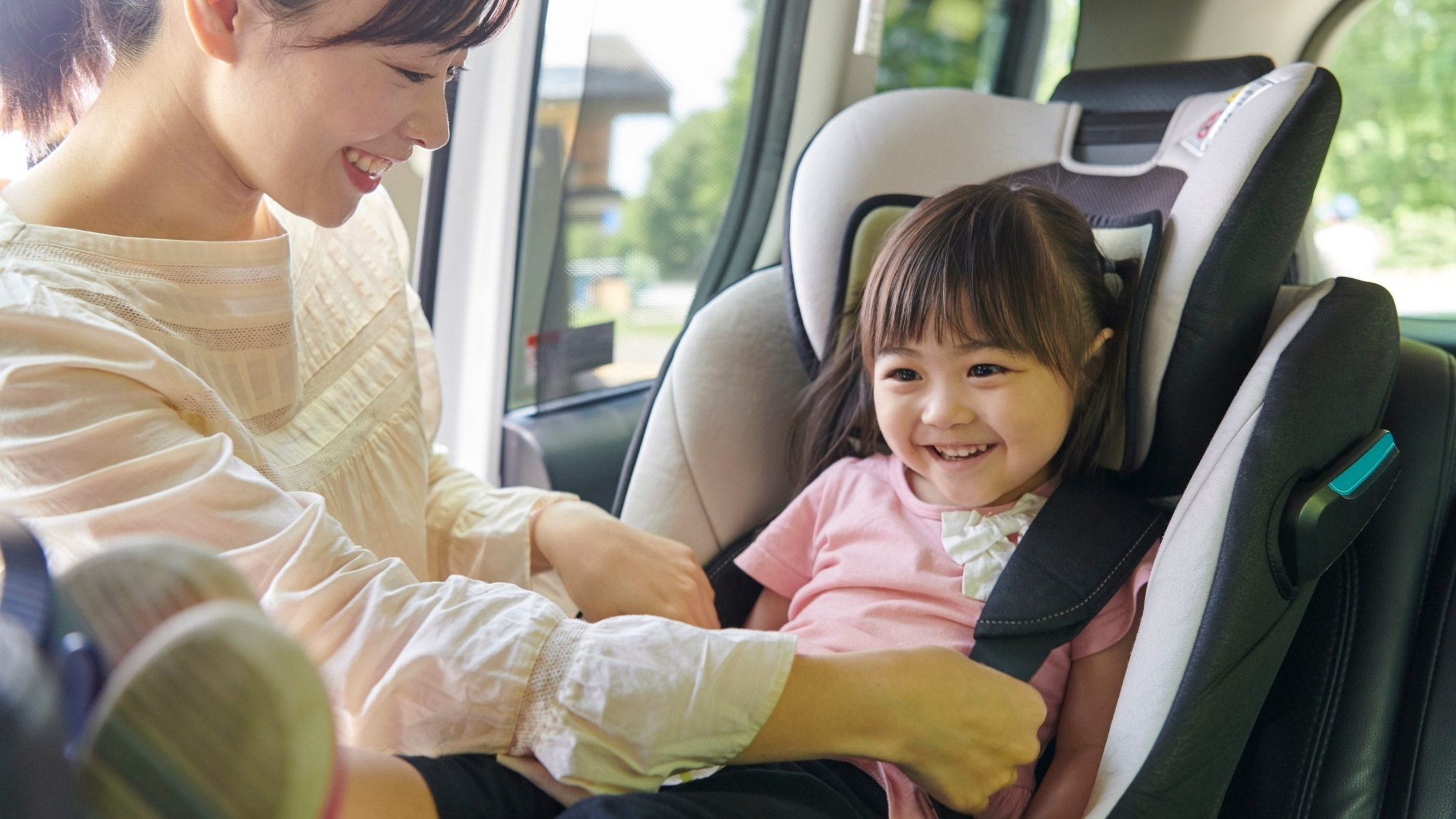 mother buckling baby into car seat