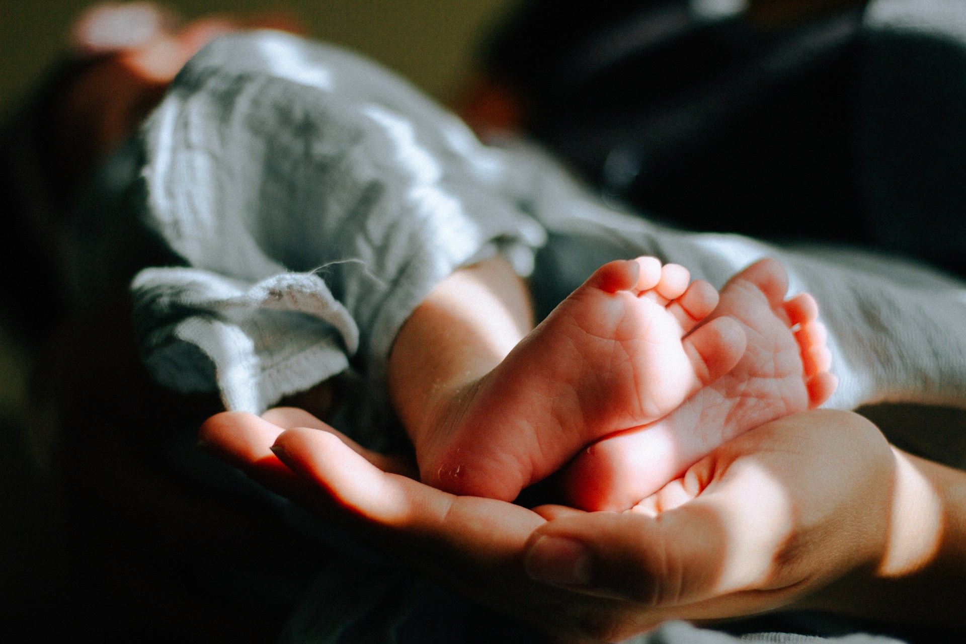 newborn baby in mothers arms, feet toward camera
