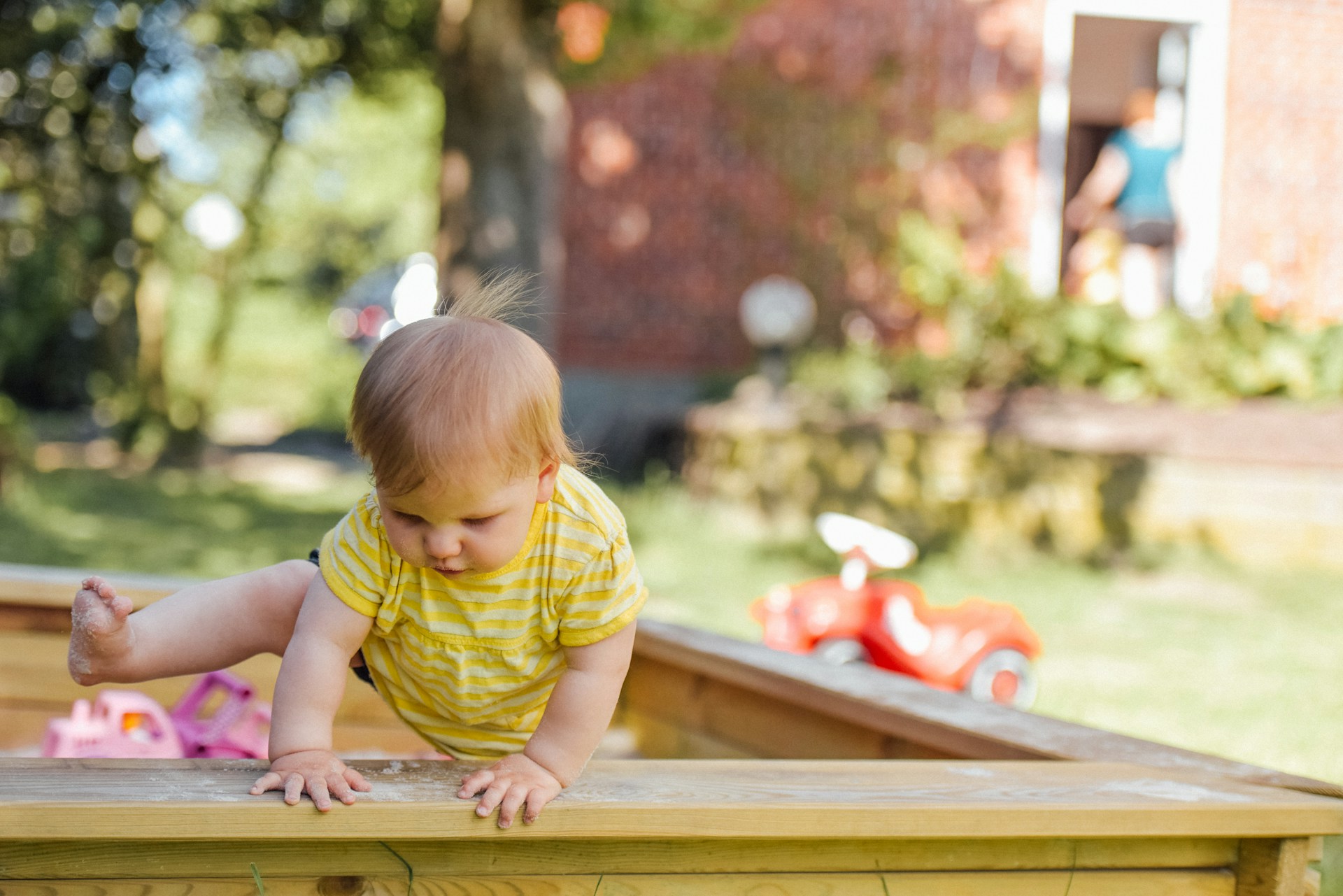 baby playing in sandbox in summer