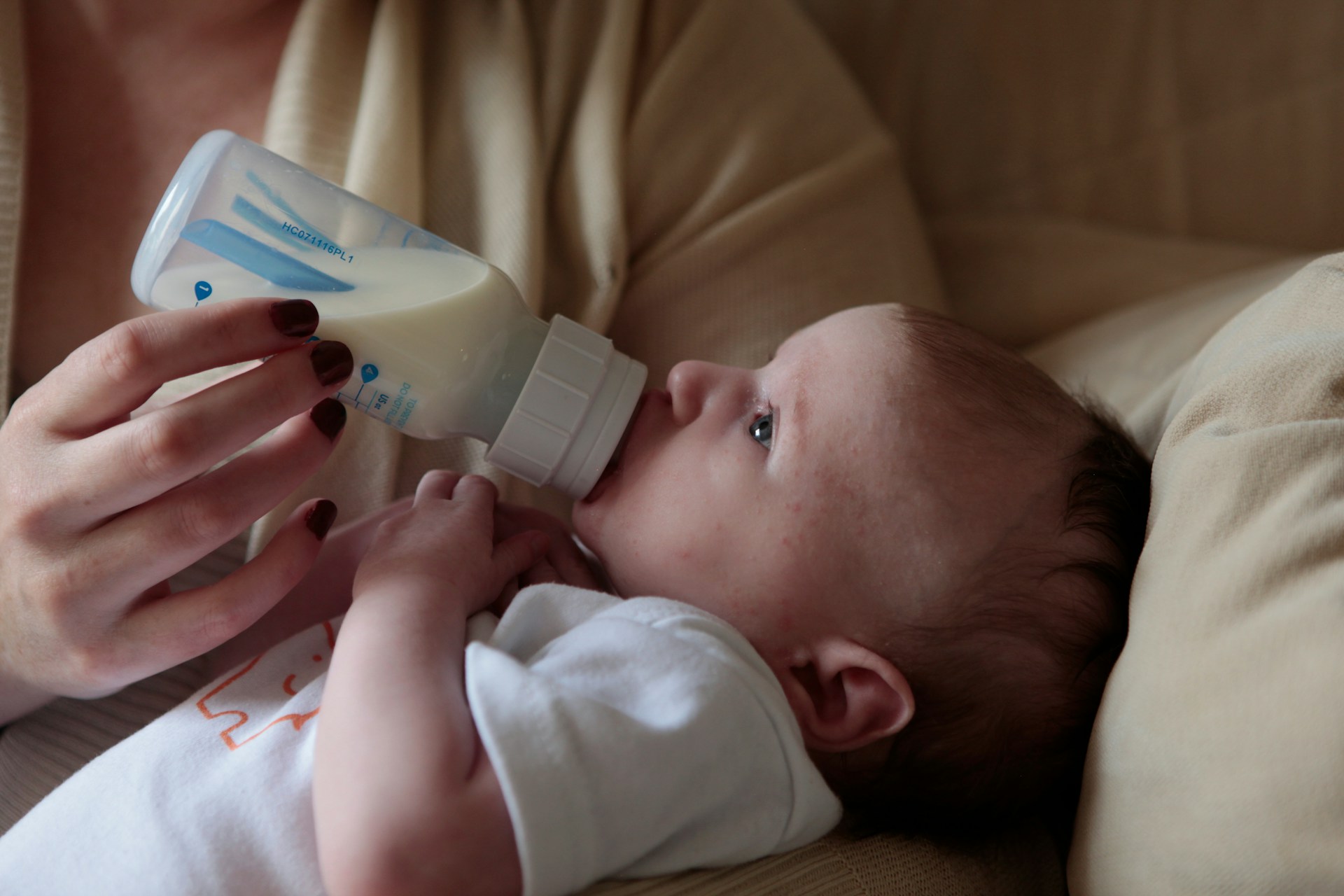 baby being fed with bottle by its mom