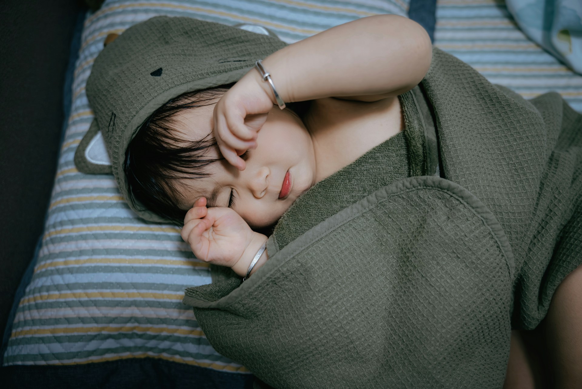 baby in green sleep sack rubbing eyes while trying to sleep