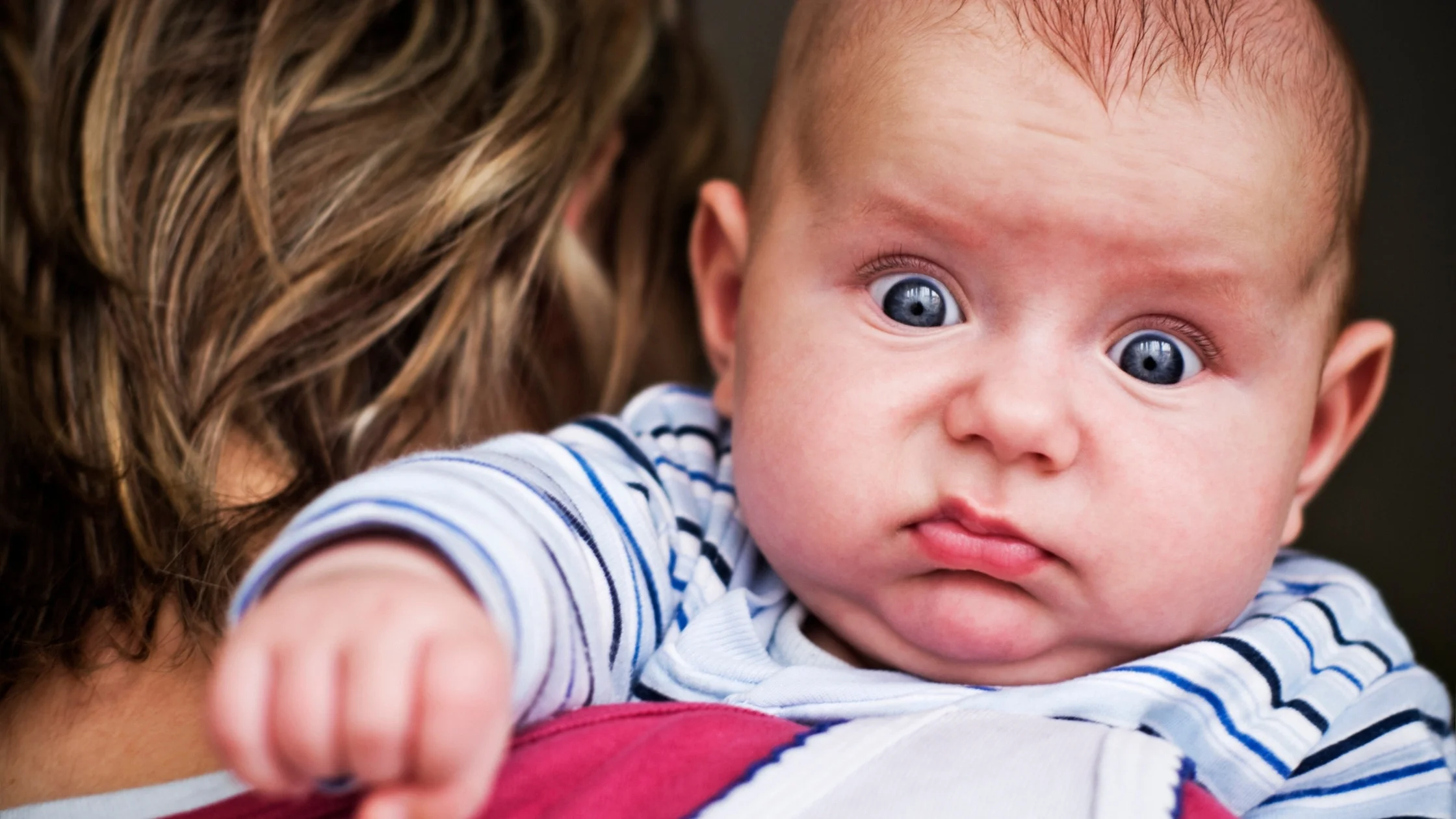 baby on mom's shoulder frowning
