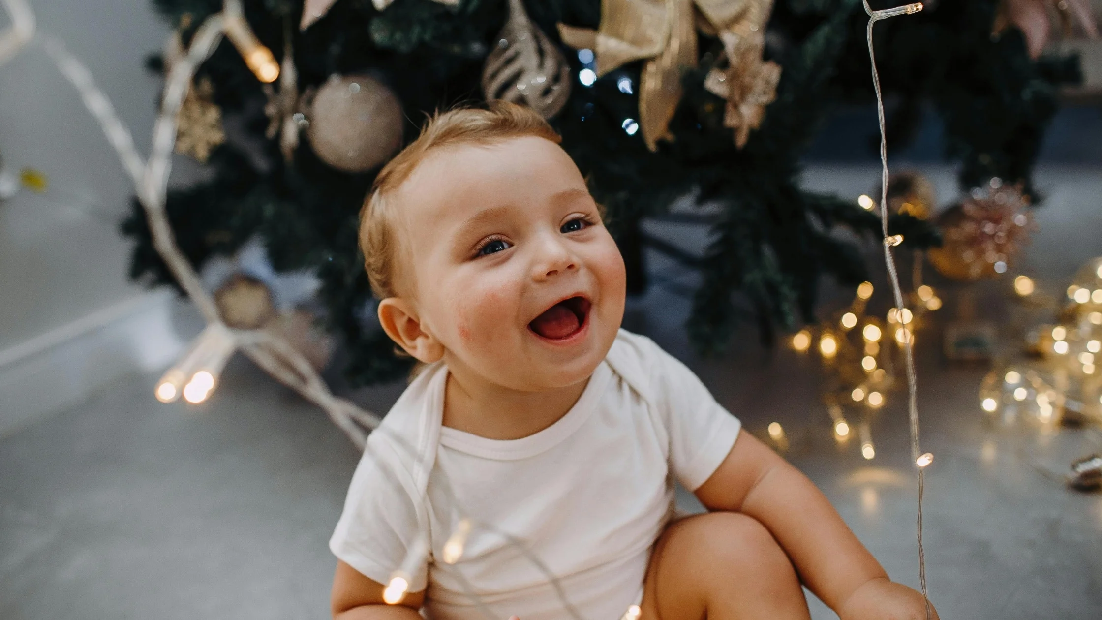 smiling baby next to a Christmas tree