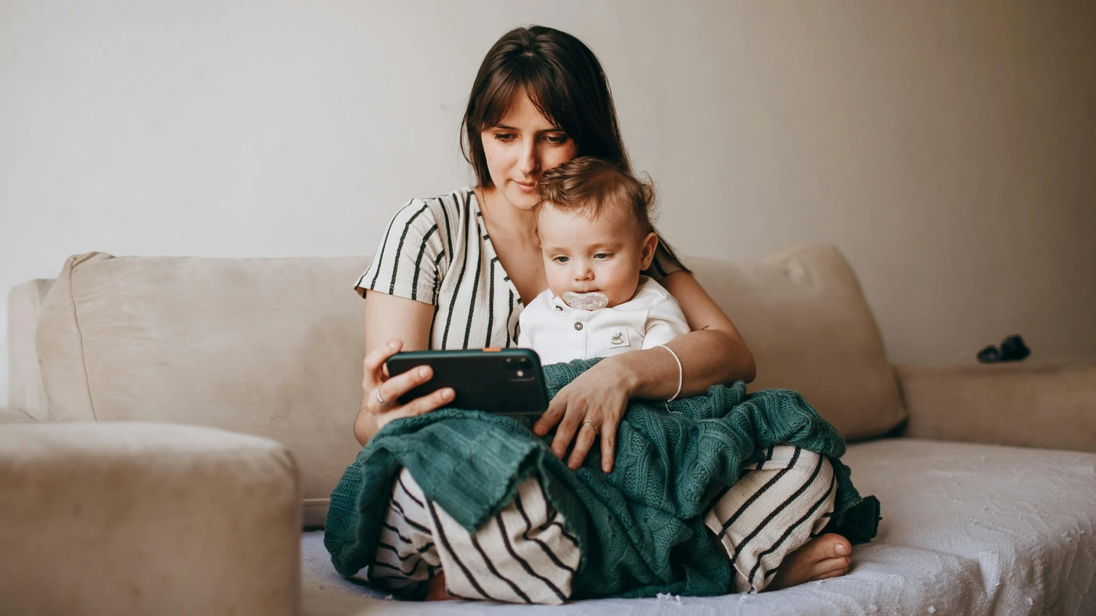 mom and baby looking at phone on couch