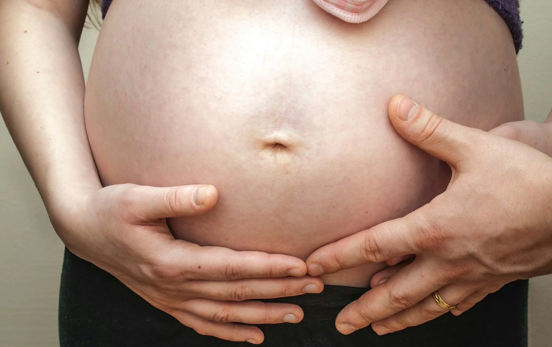 woman with pregnant belly holding her belly with her hands